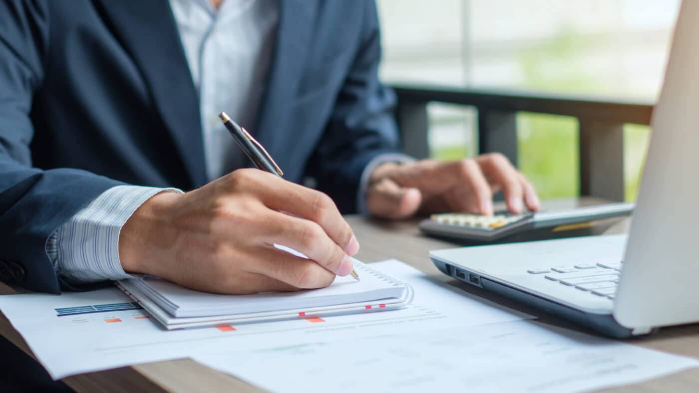 accountant working on laptop and paper with pen